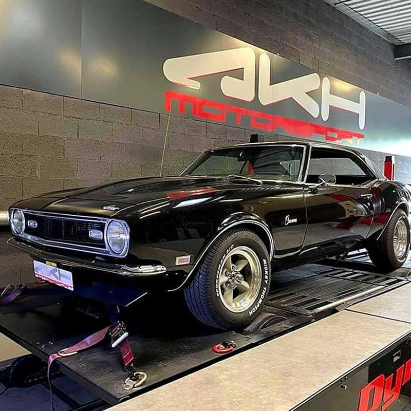 Chevy Camaro noire classique sur banc d'essai dynamomètre chez JKH MOTORSPORT, pneus Mickey Thompson. Test de puissance moteur.