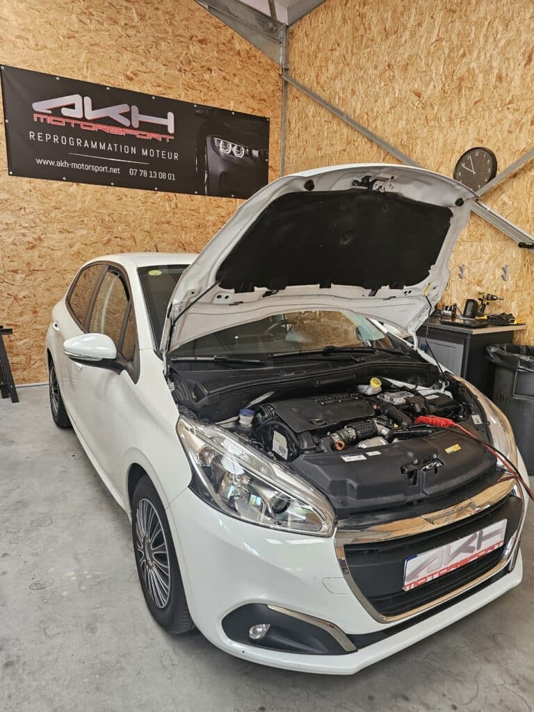 Reprogrammation moteur Peugeot 208 chez AKH Motorsport Peugeot 208 blanche capot ouvert chez AKH Motorsport pour une reprogrammation moteur professionnelle en atelier.