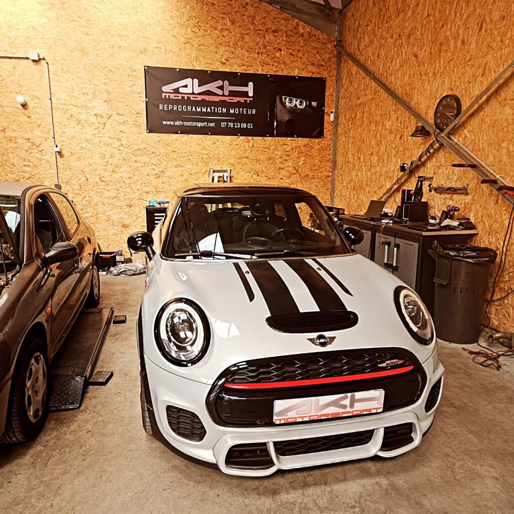 Mini Cooper JCW chez AKH Motorsport : Reprogrammation Moteur Mini Cooper JCW grise chez AKH Motorsport, atelier de reprogrammation moteur avec bandes noires sur le capot.