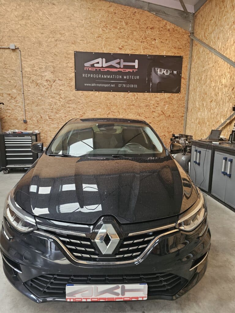 Expert en Reprogrammation Moteur Renault - AKH Motorsport Renault noire stationnée pour une reprogrammation moteur devant l'enseigne AKH Motorsport dans un atelier de performance.