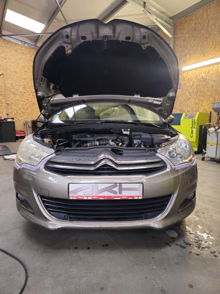 Entretien et rénovation Citroën chez AKH Motorsport Citroën grise capot ouvert chez AKH Motorsport pour rénovation de phares et entretien moteur dans un garage automobile.