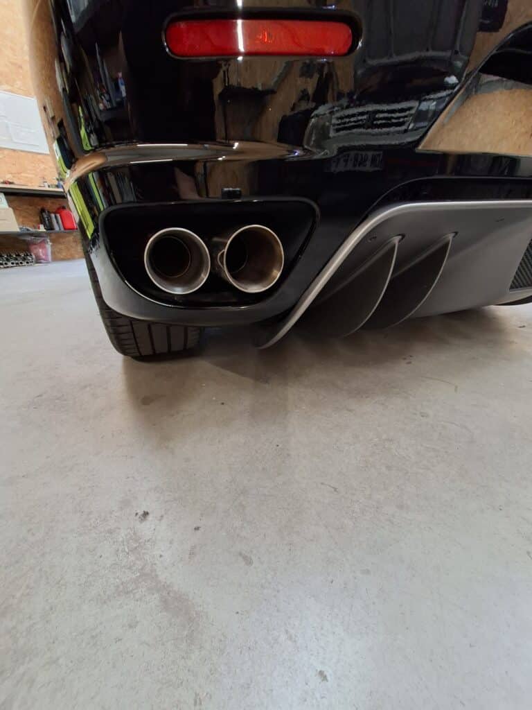Échappement et diffuseur arrière de voiture de sport noire Échappement double et diffuseur d'une voiture de sport noire dans un garage.